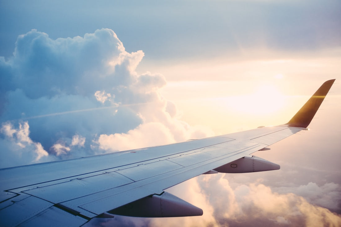 View from an airplane window looking out at calm blue sky and white clouds — hypnotherapy for fear of flying