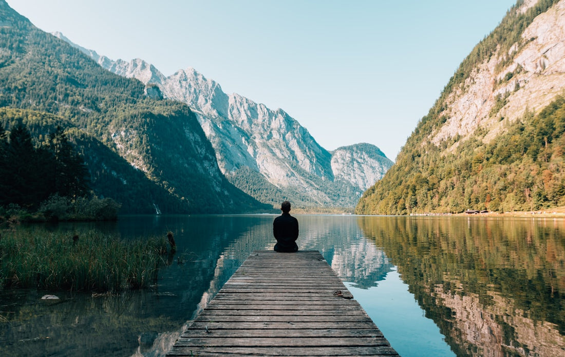 Person meditating peacefully by the ocean, representing hope and recovery from depression through hypnotherapy