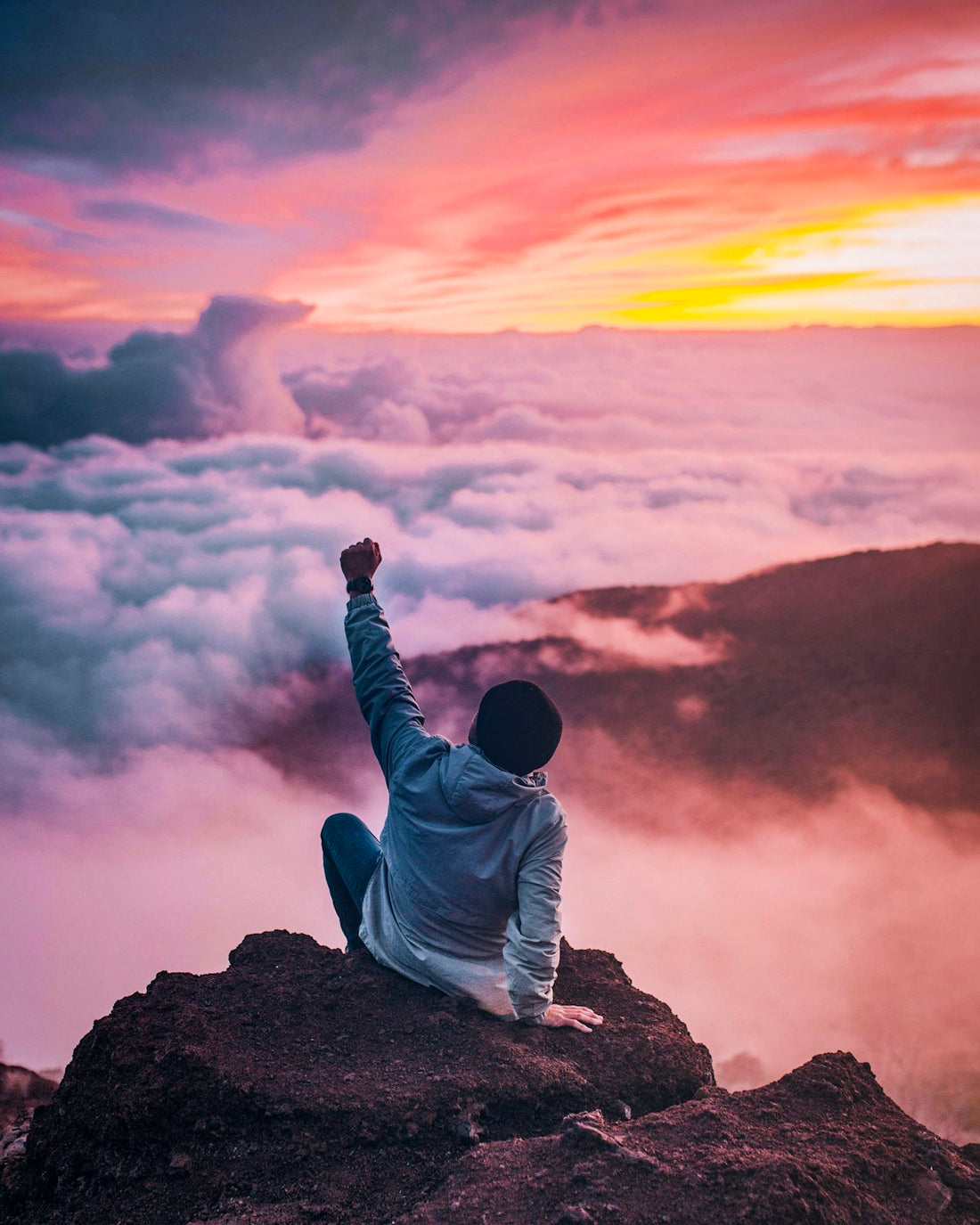Person standing at a mountain peak representing overcoming fear of failure with hypnotherapy