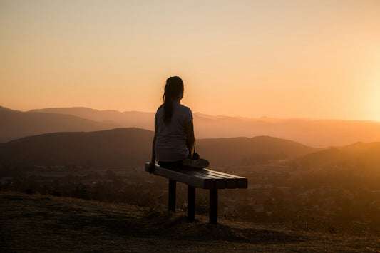 Woman sitting peacefully outdoors with eyes closed, breathing calmly — representing relief from overwhelm through hypnotherapy