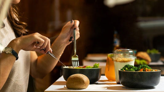Woman eating mindfully and peacefully at a table, representing a healthy relationship with food supported by hypnotherapy